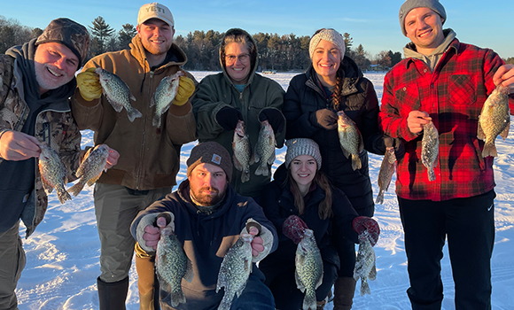 Group of people ice fishing holding fish